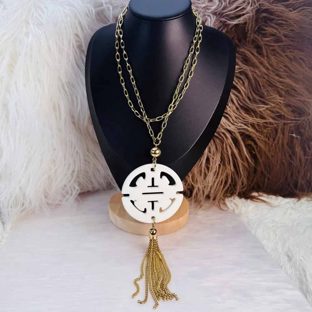 Long, goldtone, costume necklace, with large white pendant, and metal fringe